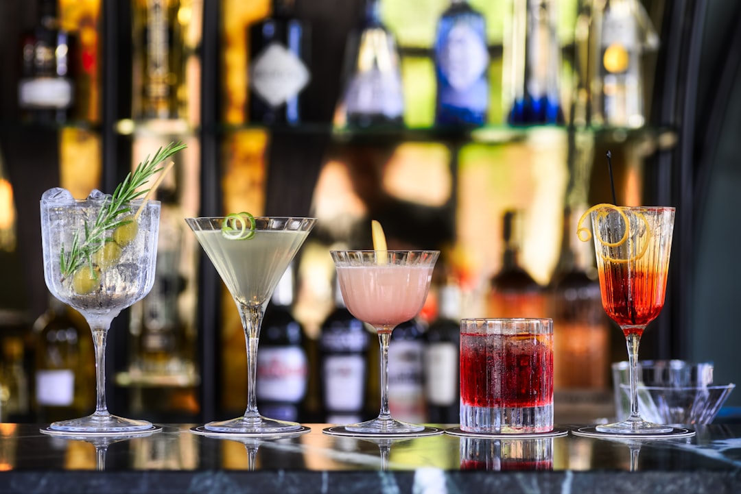 Four colorful mocktails with various fruit garnishes and straws