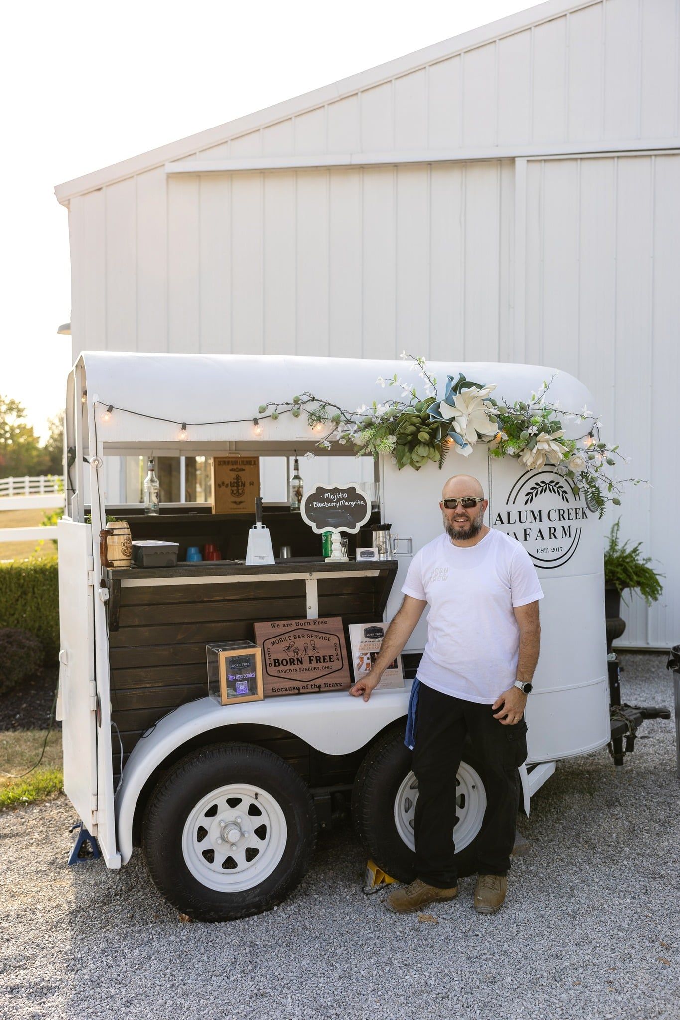 Bartender using a shaker in a mobile bar trailer, full view