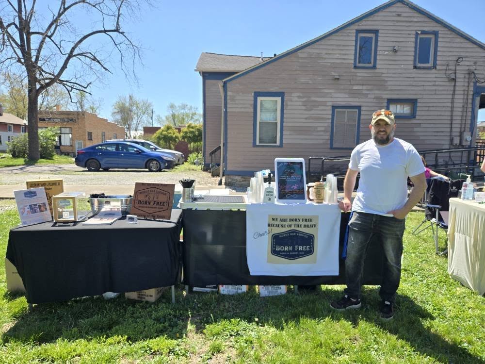 Founder Randy and a pregnant staff member smiling at an outdoor bar setup