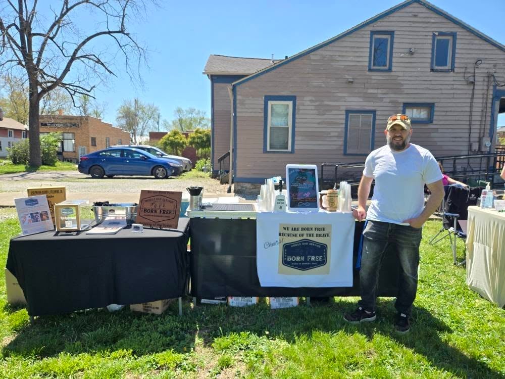 Founder Randy smiling in front of the Alum Creek Farm mobile bar with floral decor